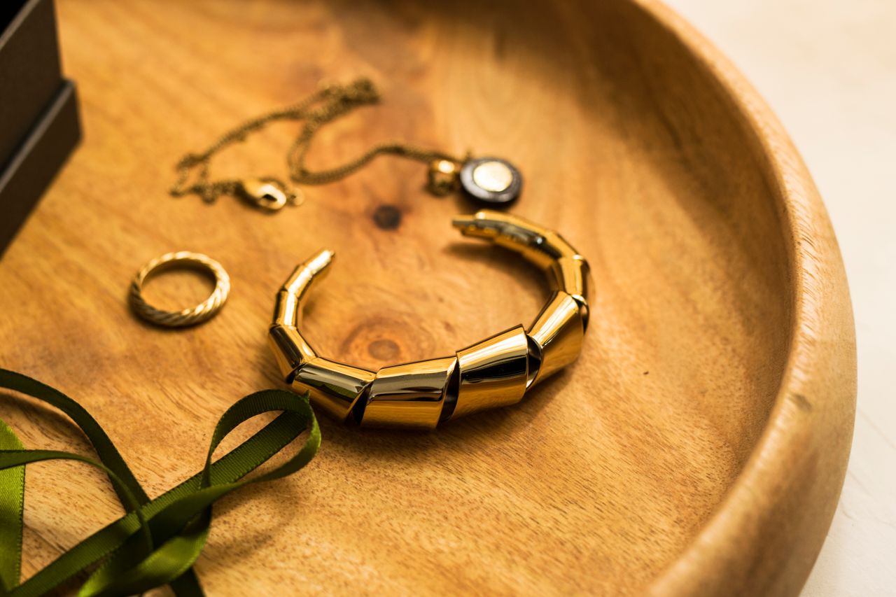 The Art of Drawing Readers In: Your attractive post title goes here Close-up of stylish gold jewelry including a bracelet, ring, and pendant on a wooden tray.