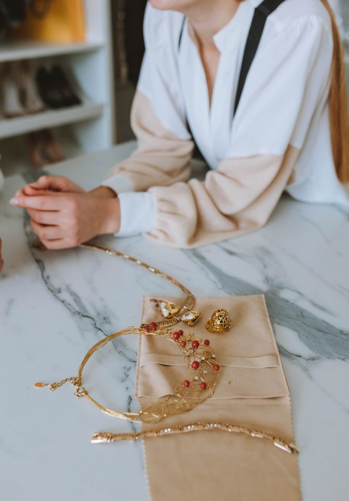 Crafting Captivating Headlines: Your awesome post title goes here A woman enjoys elegant jewelry displayed on a marble counter indoors.